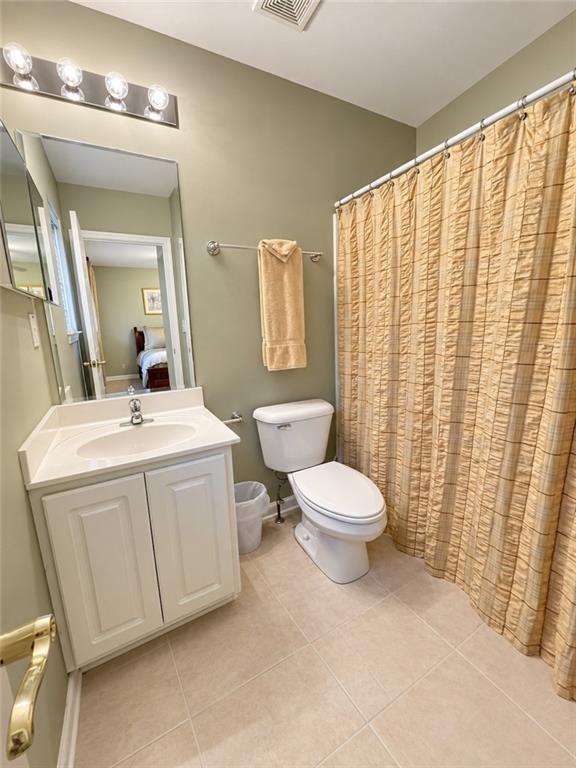 Bathroom with a white vanity, toilet, and tan gathered shower curtain.