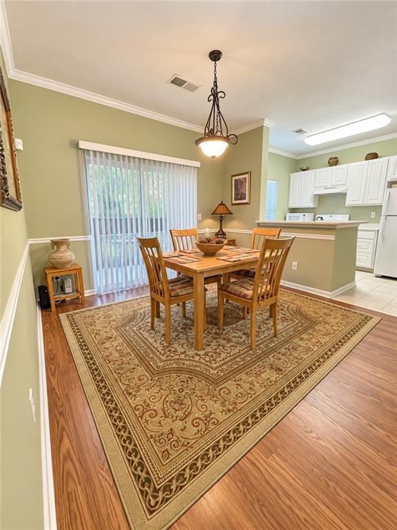 Dining room with a wooden table and chairs on an ornate rug beside sliding glass doors.