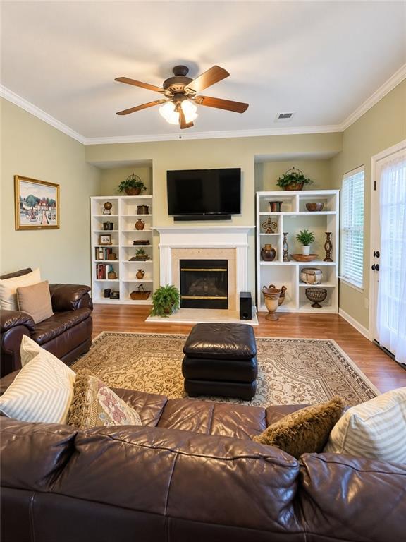 Living room with leather sofas, a fireplace, built-in shelves, and a television.