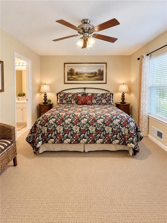 Bedroom with a floral-covered bed, matching bedside lamps, and a ceiling fan.
