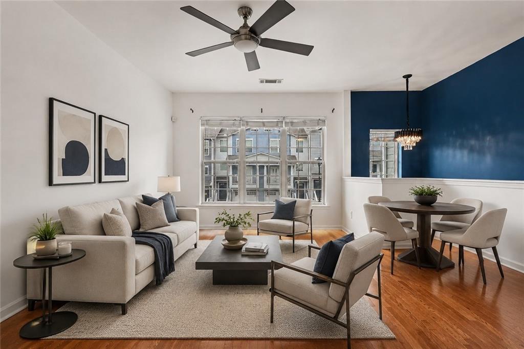Staged open-plan living and dining room with a navy accent wall and large windows.