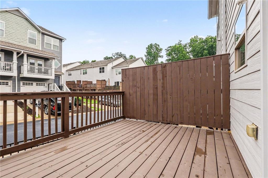 Elevated wooden deck with a tall privacy fence overlooking neighboring homes.