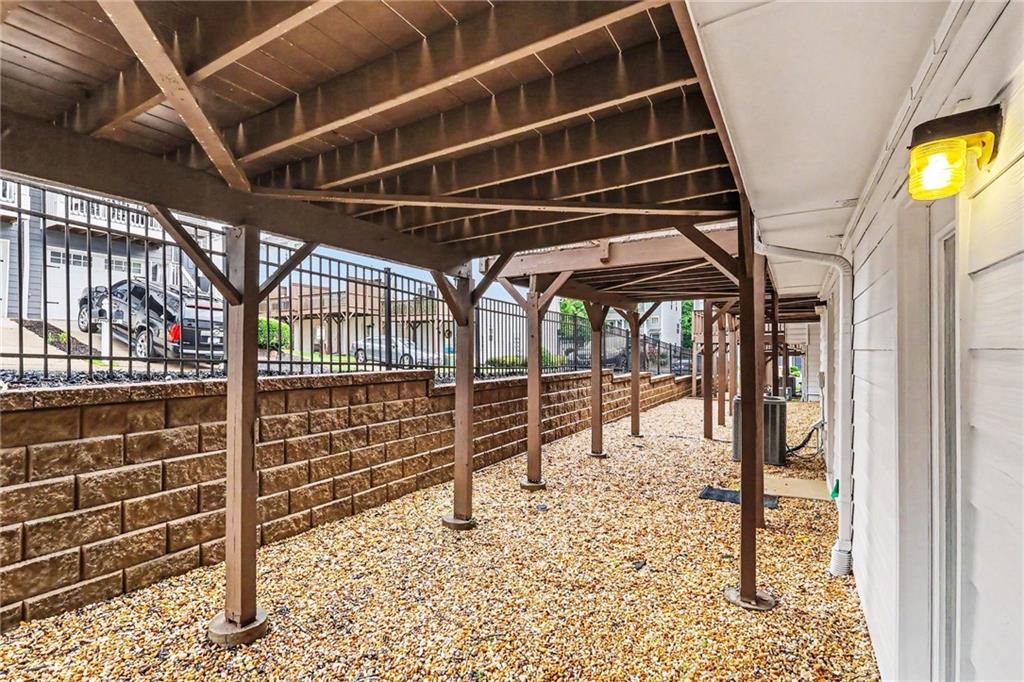 Gravel side yard beneath a raised wooden deck, bordered by a block retaining wall.