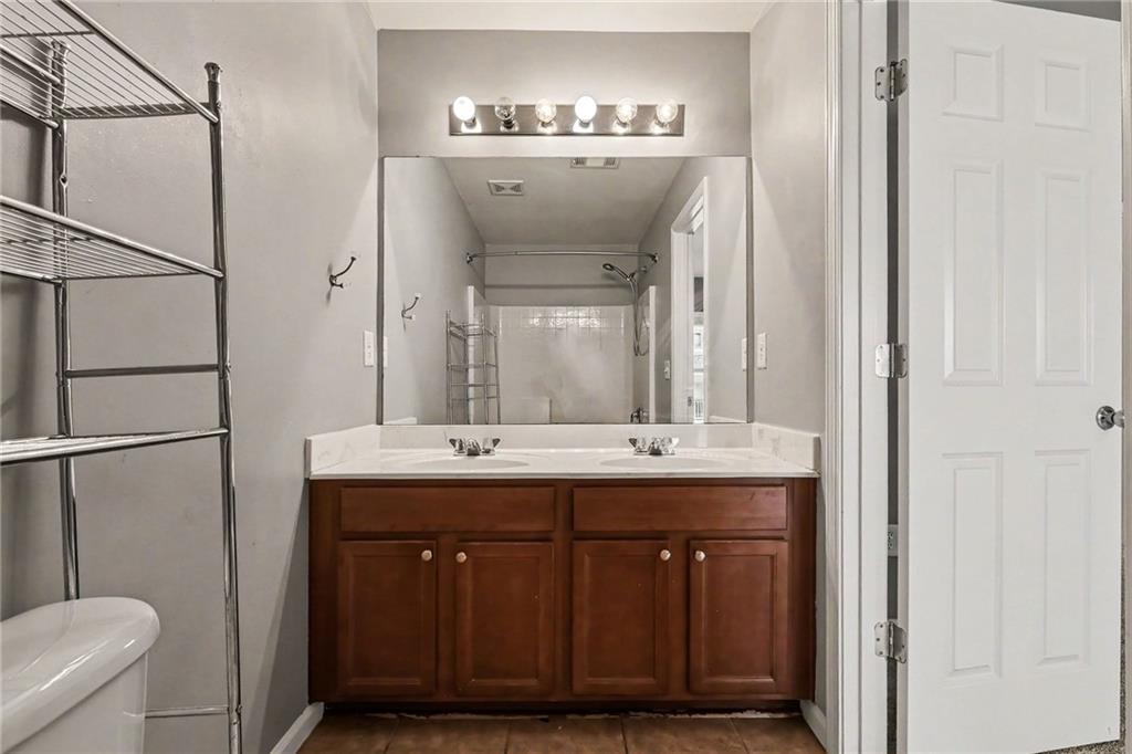 Bathroom with double-sink vanity, dark wood cabinets, and large mirror.