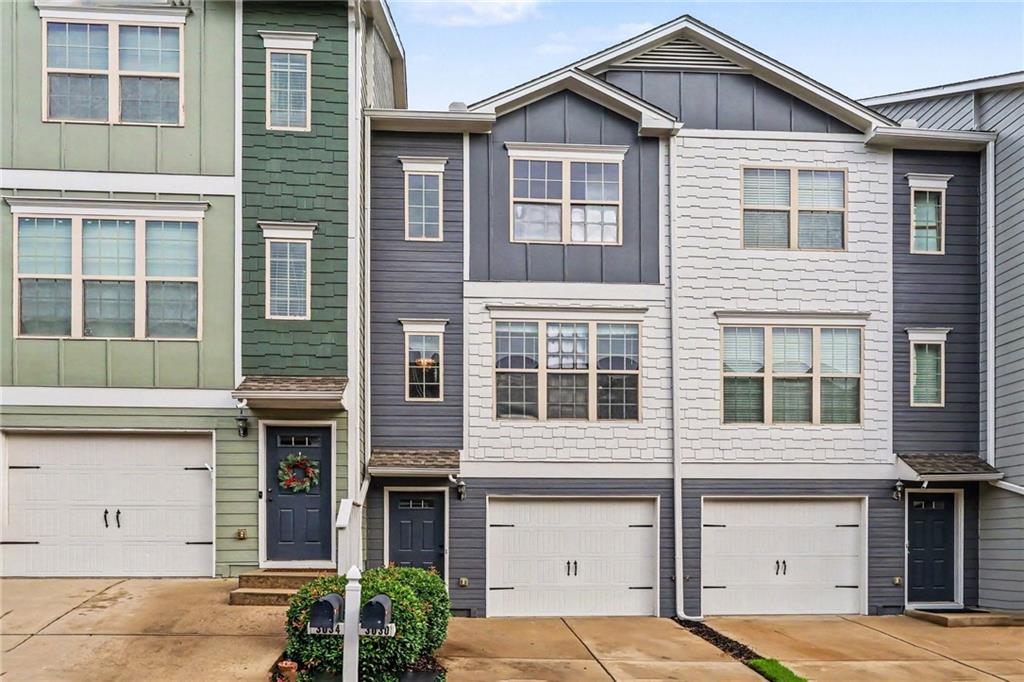 Multistory townhouse with gray and white siding, a single-car garage, and a front entrance.