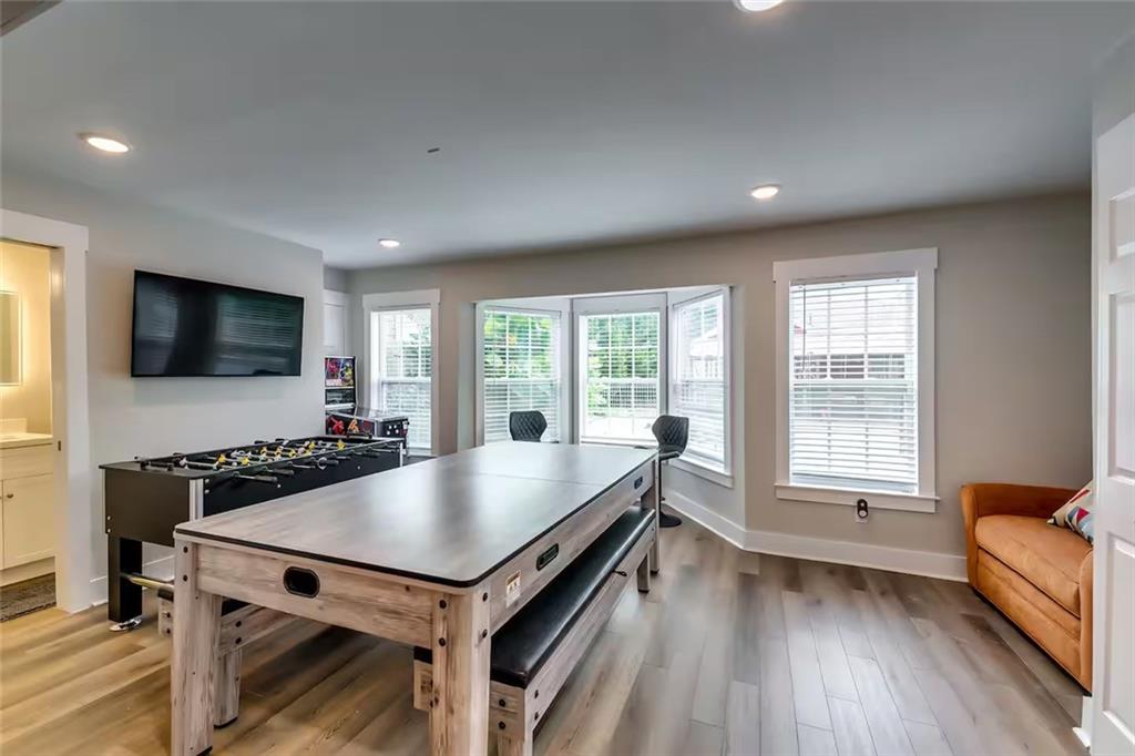 Game room with a large pool table, foosball table, wall-mounted television, and tan sofa.