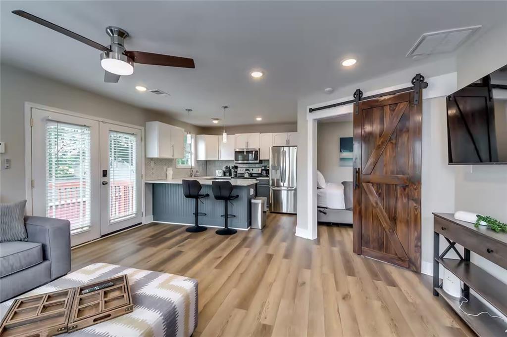 Open-plan living room and kitchen with a dark island and sliding barn door.