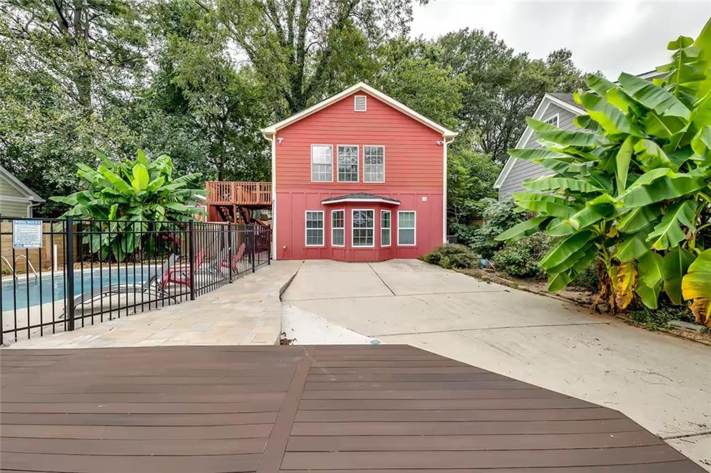 Rear exterior of a red two-story home with a fenced pool and wood deck.