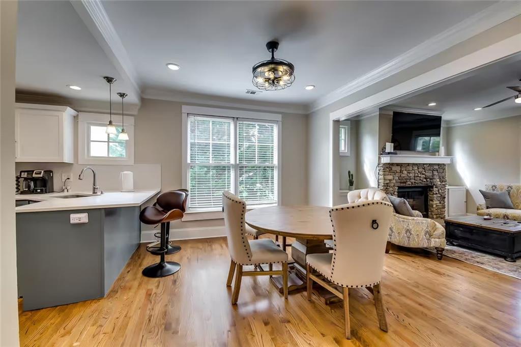 Open-plan kitchen and dining area with hardwood floors, a round table, and adjoining living room with stone fireplace.