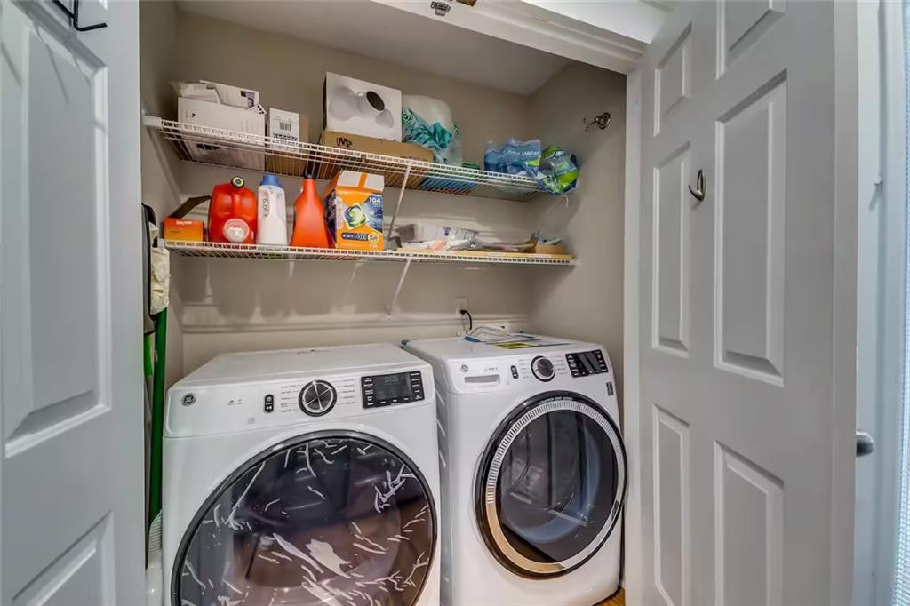 Laundry room with front-loading washer and dryer beneath stocked wire shelves.