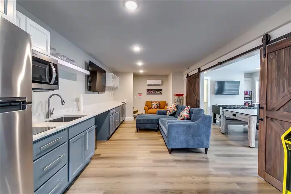 Open kitchen and game room with blue-gray cabinets, a blue sectional, barn doors, and a foosball table.
