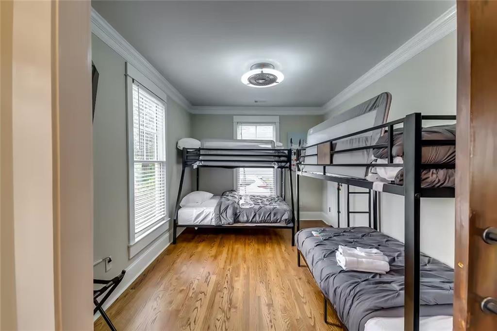 Bedroom with black metal bunk beds, gray bedding, folded towels, and hardwood floors.