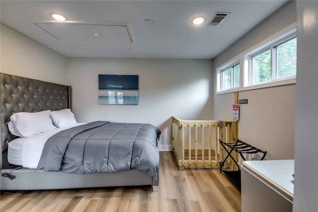 Bedroom with a gray tufted bed, high windows, and a wooden safety gate.