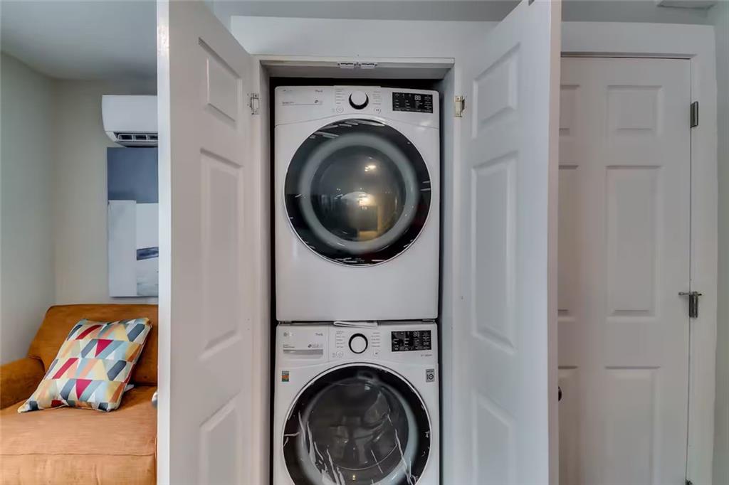 Stacked washer and dryer tucked into an open laundry closet beside a living area.