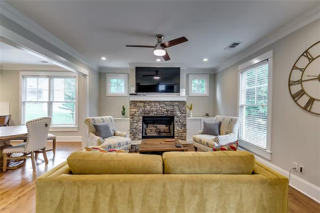 Living room with a stone fireplace, ceiling fan, and mustard-yellow sofa.