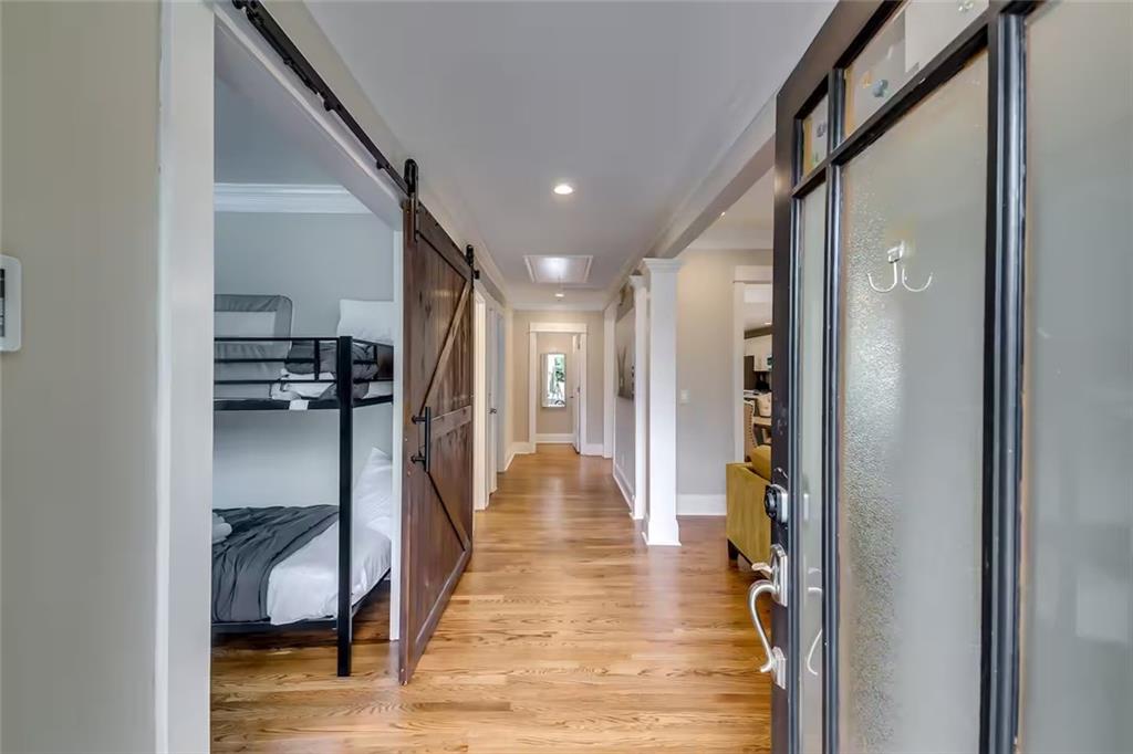 Entry hallway with hardwood floors, a sliding barn door, and a bunk bed visible in an adjoining room.