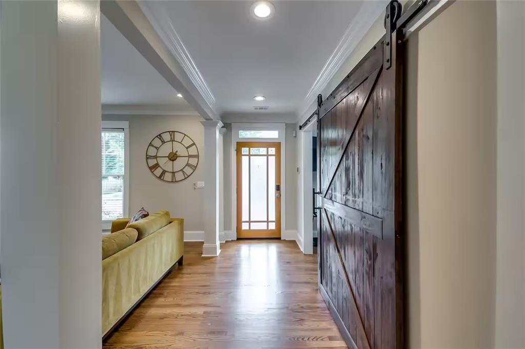 Entryway with wood floors, a glass-paneled front door, and a dark sliding barn door beside the living area.