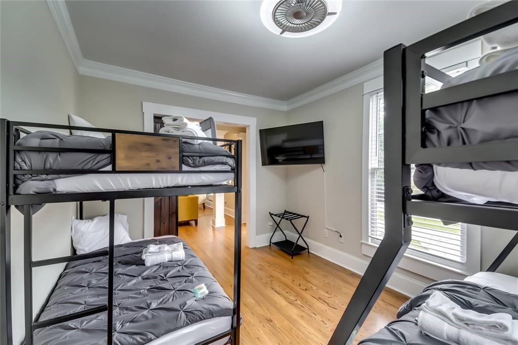 Bedroom with black metal bunk beds, gray bedding, and a wall-mounted TV.