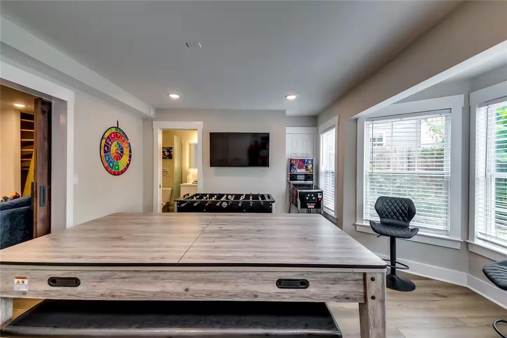 Game room with a large table, foosball table, arcade game, and wall-mounted TV.