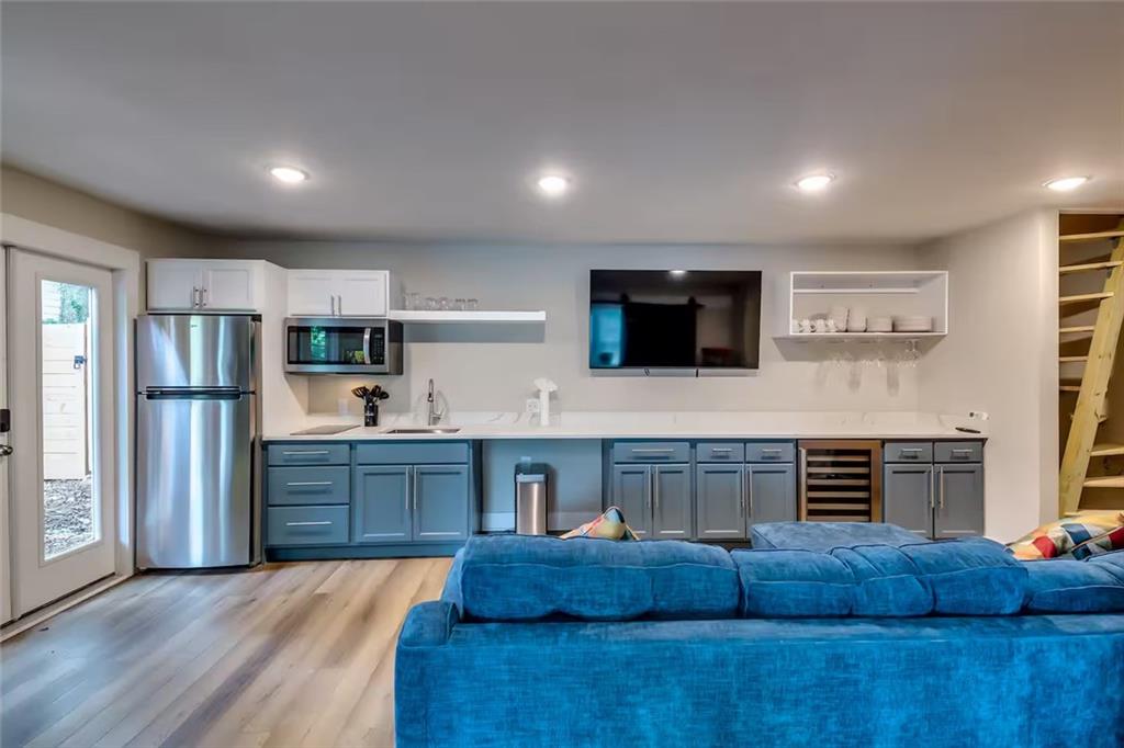 Kitchen and living area with blue cabinets, stainless appliances, and a blue sectional sofa.