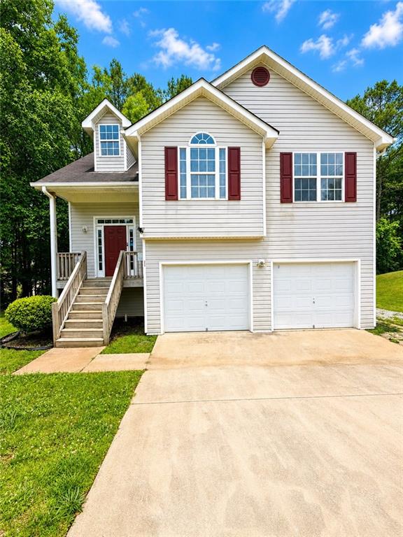 Two-story light-sided house with burgundy shutters, twin garage doors, and a raised front porch.