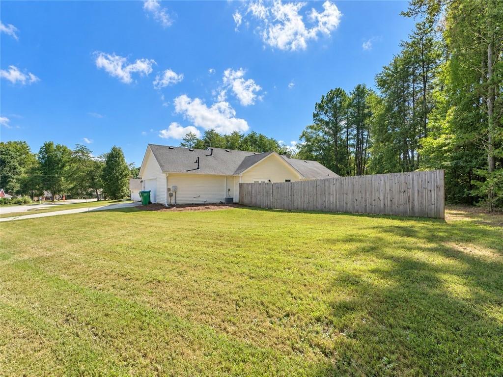 Home’s side exterior beside a broad lawn and tall wooden privacy fence.