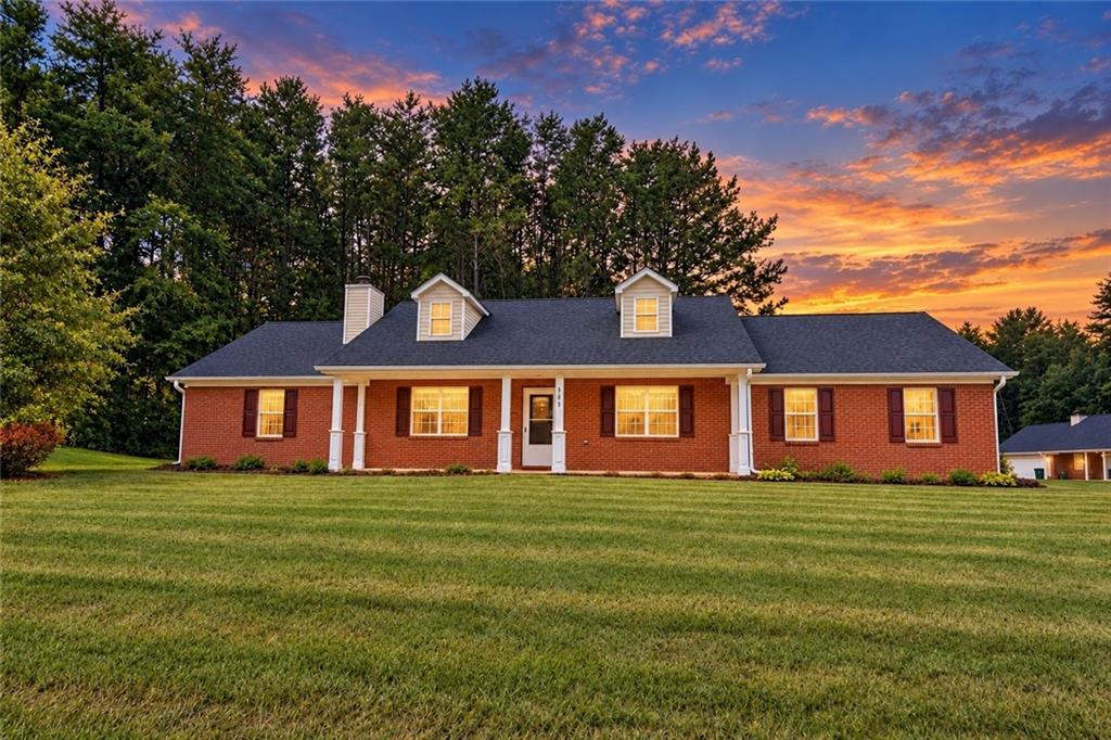 Red brick home with white porch columns and dormers, warmly lit at sunset.