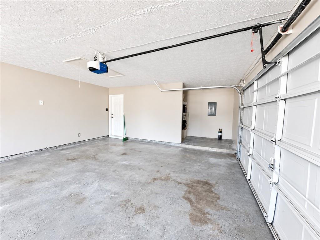 Empty garage with a concrete floor, white overhead door, and ceiling-mounted opener.
