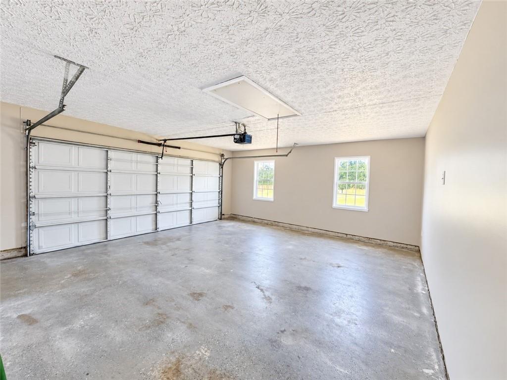 Empty two-car garage with white doors, a concrete floor, and two windows.