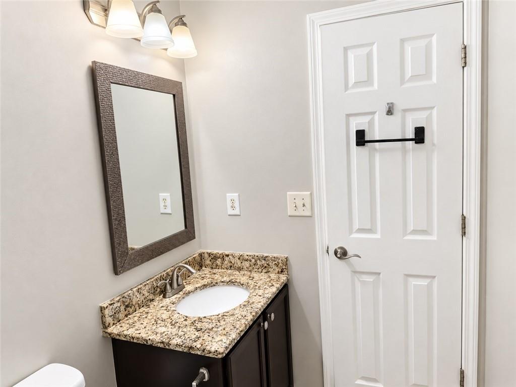 Bathroom vanity with a speckled granite countertop and framed mirror beside a white paneled door.