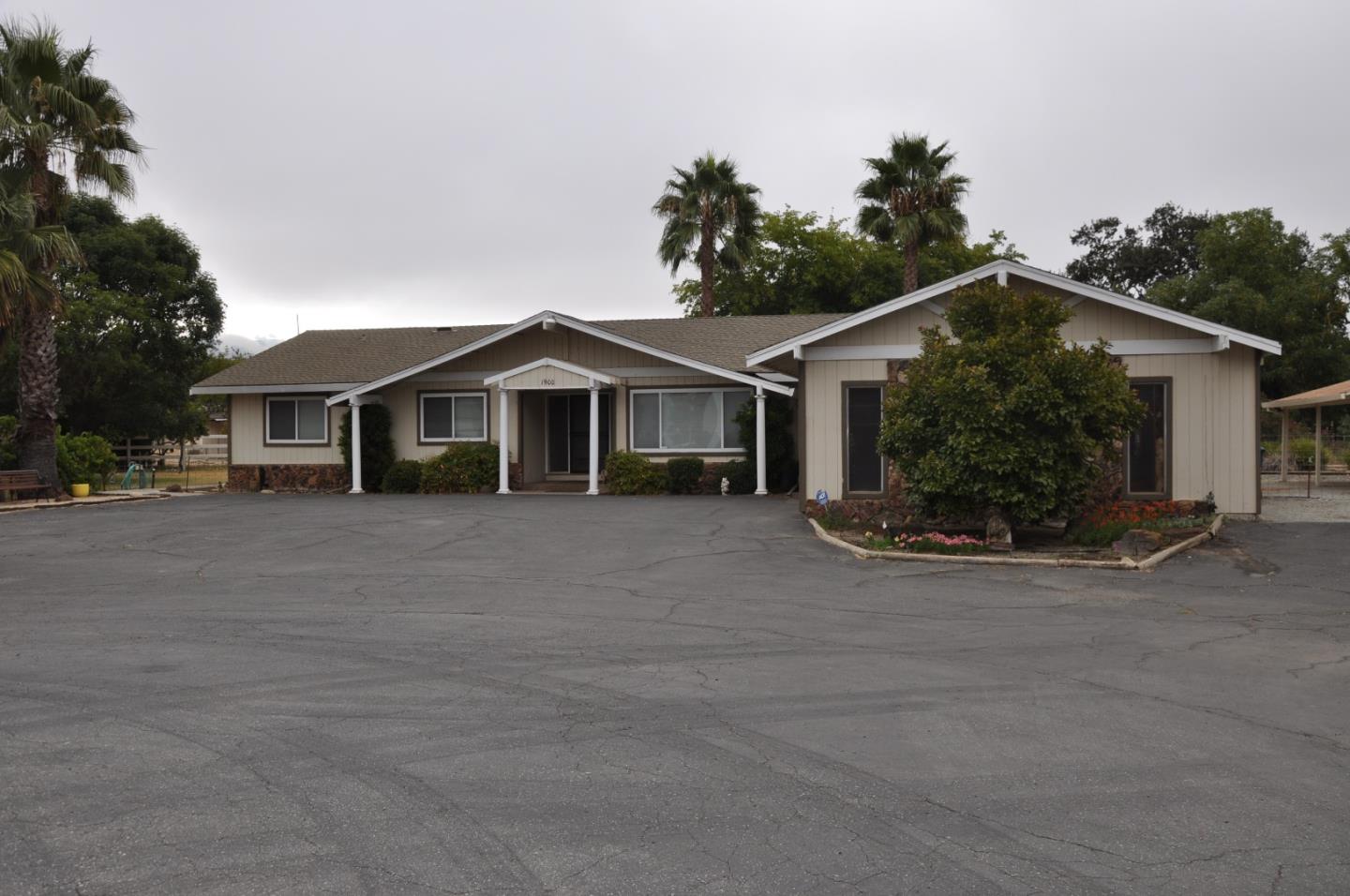 Single-story building with a broad paved parking area, landscaped shrubs, and palm trees.