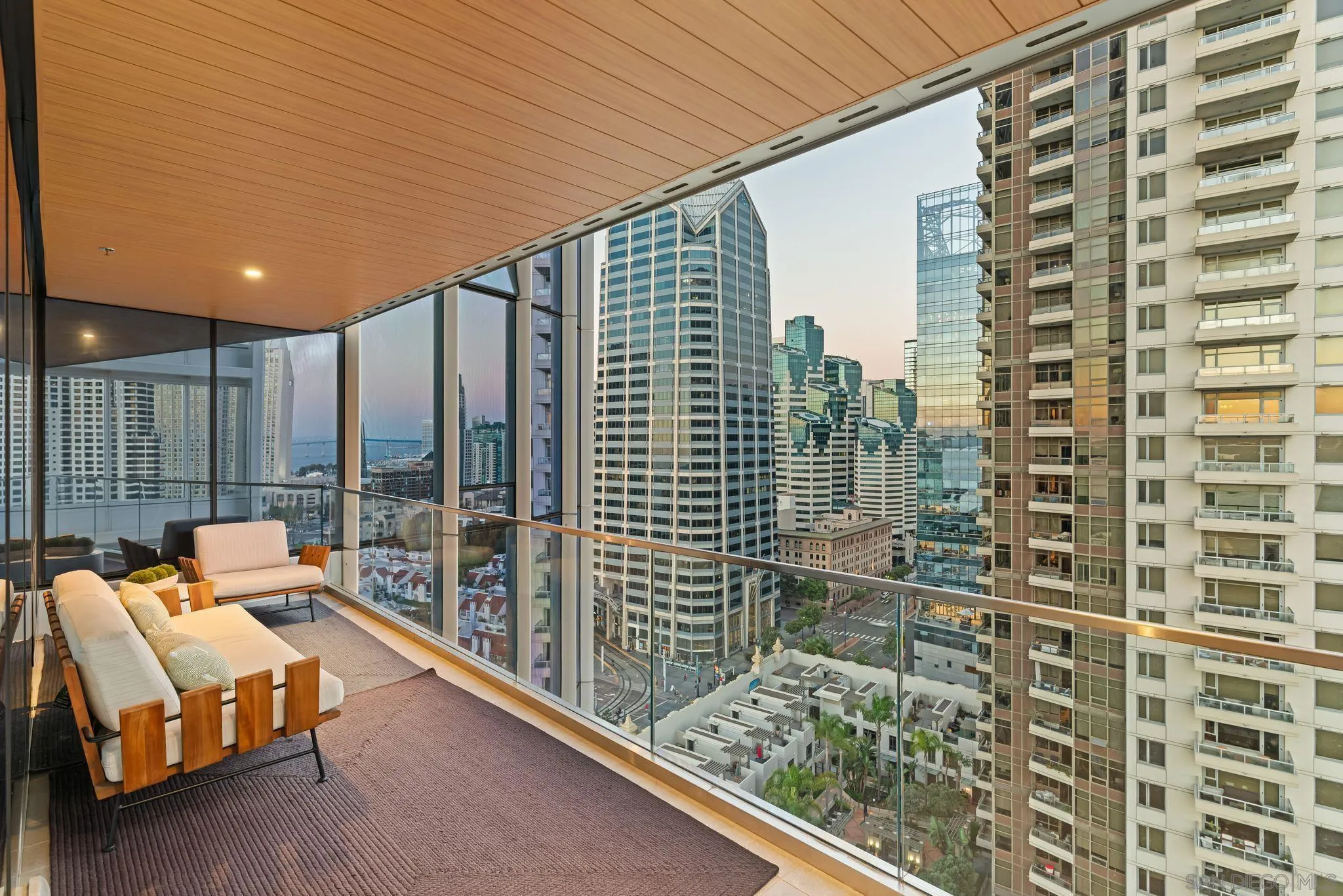 Furnished high-rise balcony with a wood ceiling and sweeping downtown skyline views.