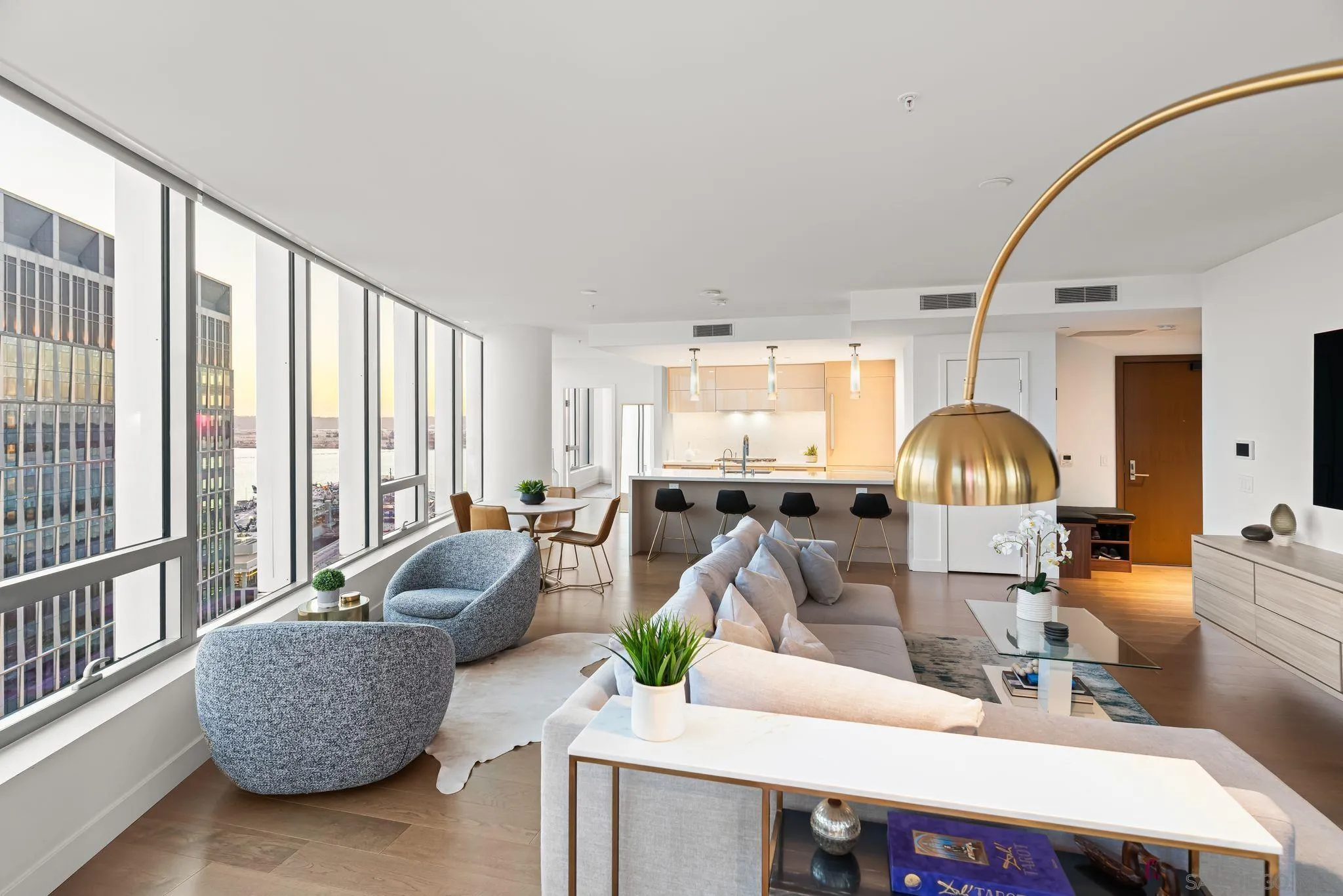 Staged condo living room with floor-to-ceiling windows, water views, and an open kitchen.