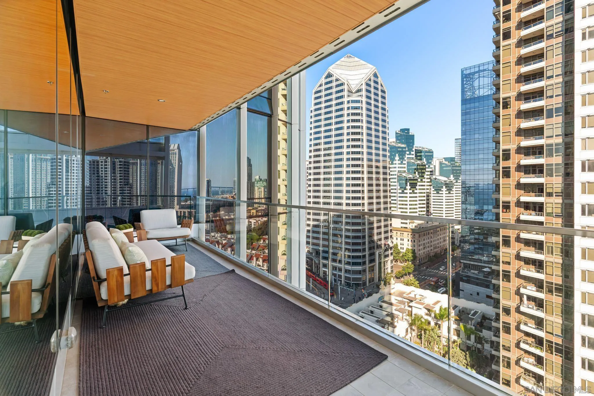 High-rise balcony with white lounge seating and a panoramic downtown skyline view.