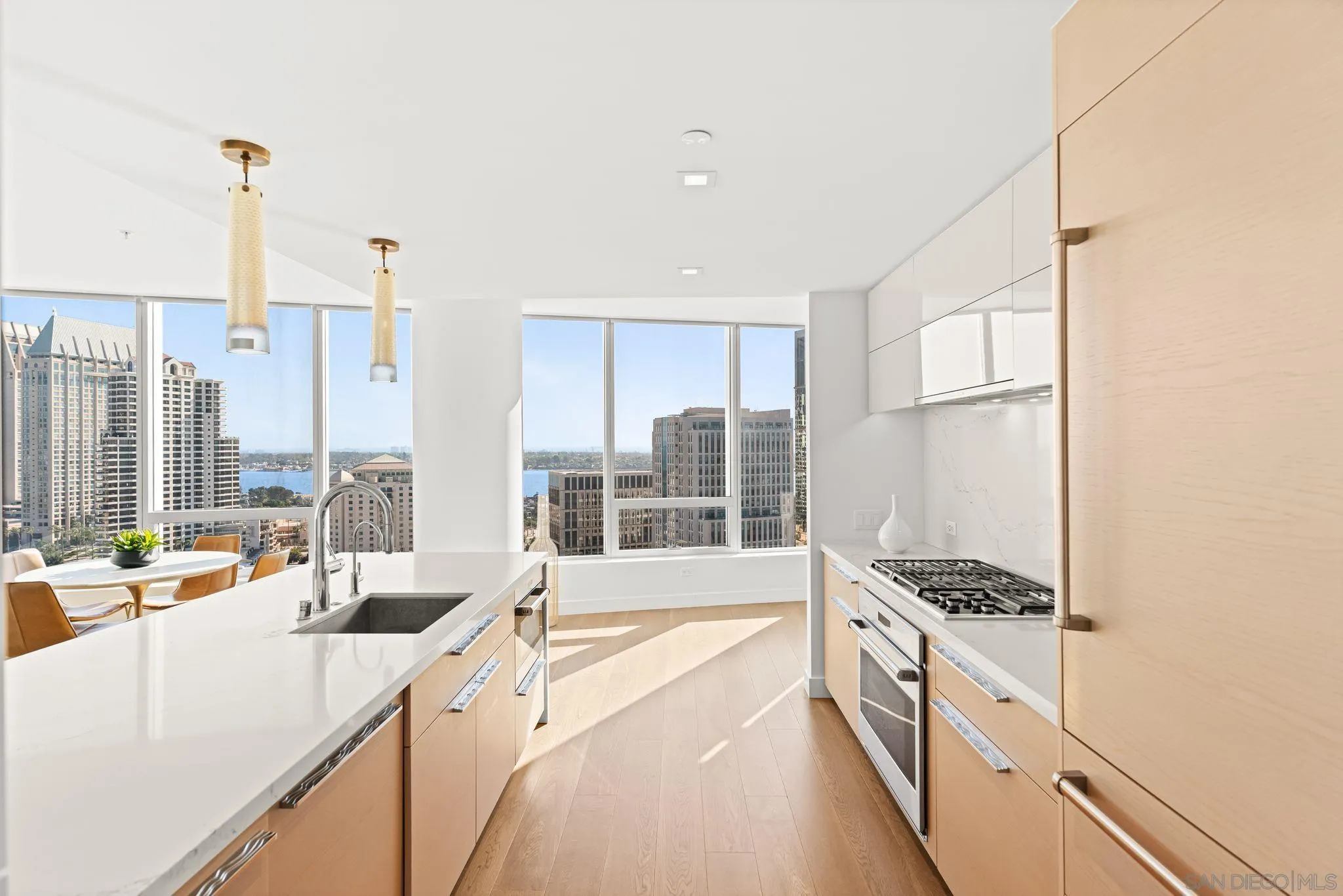 Modern condo kitchen with a white island and city and bay views through floor-to-ceiling windows.