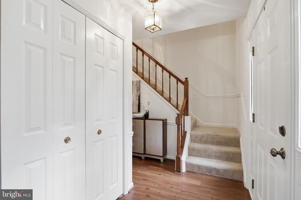 Entry foyer with a carpeted staircase, wooden railing, and white paneled doors.