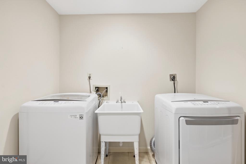 Laundry room with a top-loading washer, front-loading dryer, and utility sink.
