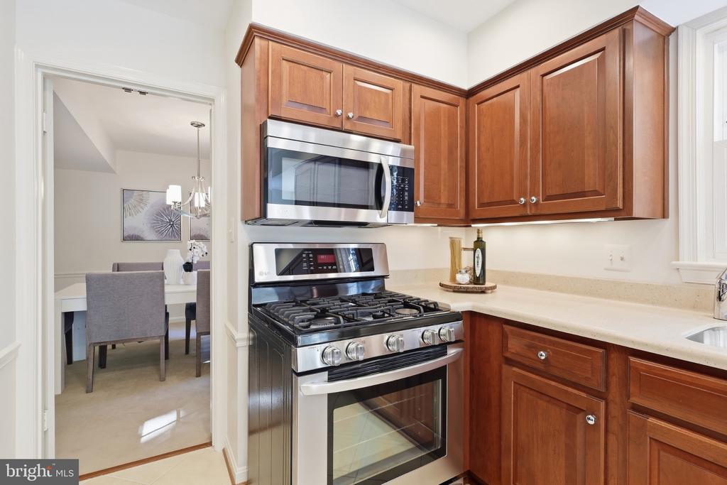 Kitchen with wood cabinetry, stainless steel appliances, and a doorway to the dining area.
