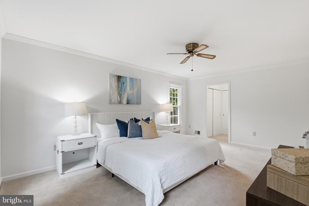 Staged bedroom with a white bed, blue and beige pillows, matching nightstands, and abstract artwork.