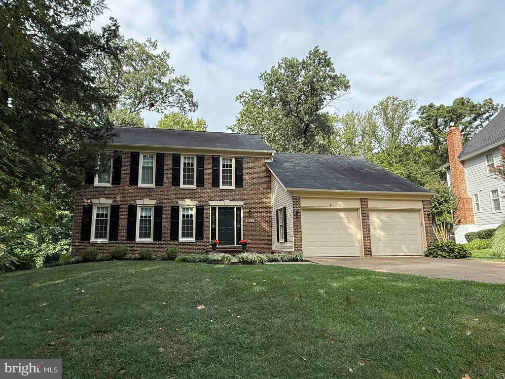 Two-story brick home with black shutters, a two-car garage, and a broad front lawn.