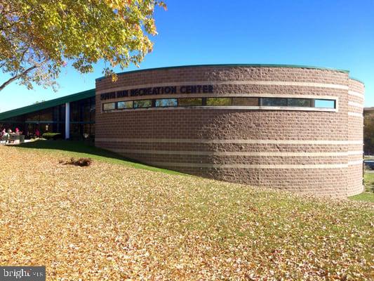Springfield Recreation Center’s curved brick exterior beside a leaf-covered lawn.