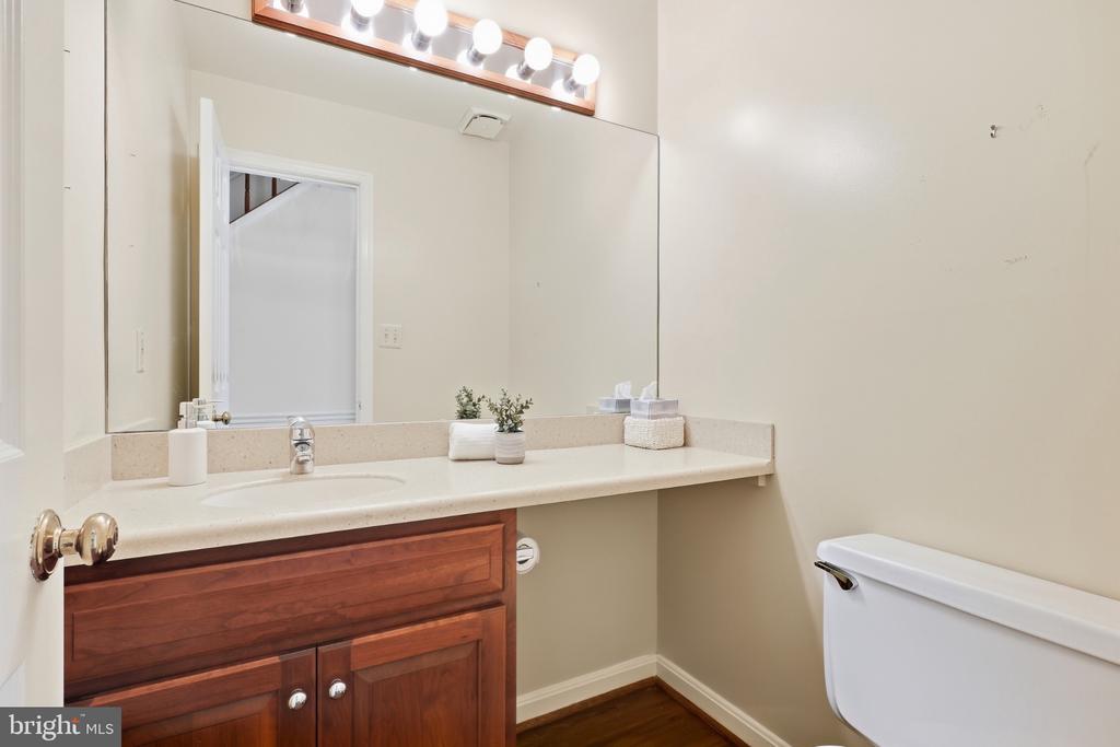 Bathroom with a dark wood vanity, wide mirror, and toilet.