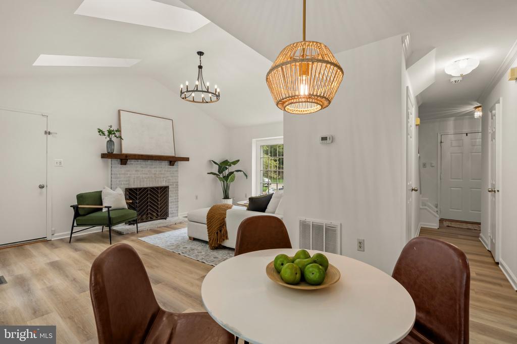 Open living and dining area with a brick fireplace, white sofa, and round table beneath woven pendant lights.