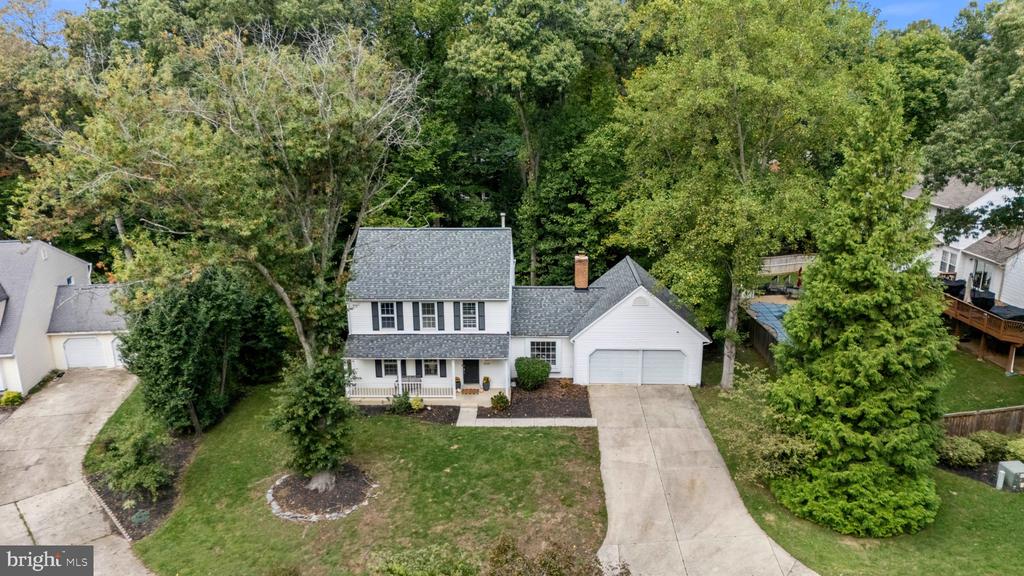 Aerial view of a white two-story house with an attached garage and mature trees.