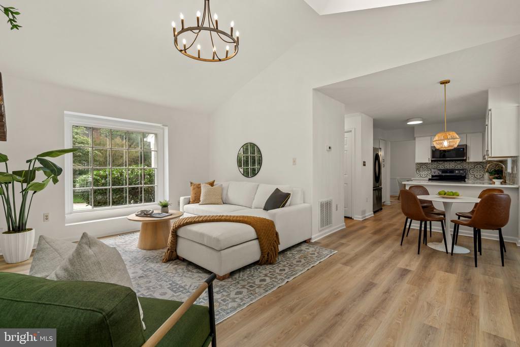 Open-plan living room and kitchen with a white sectional, patterned rug, and dining area.
