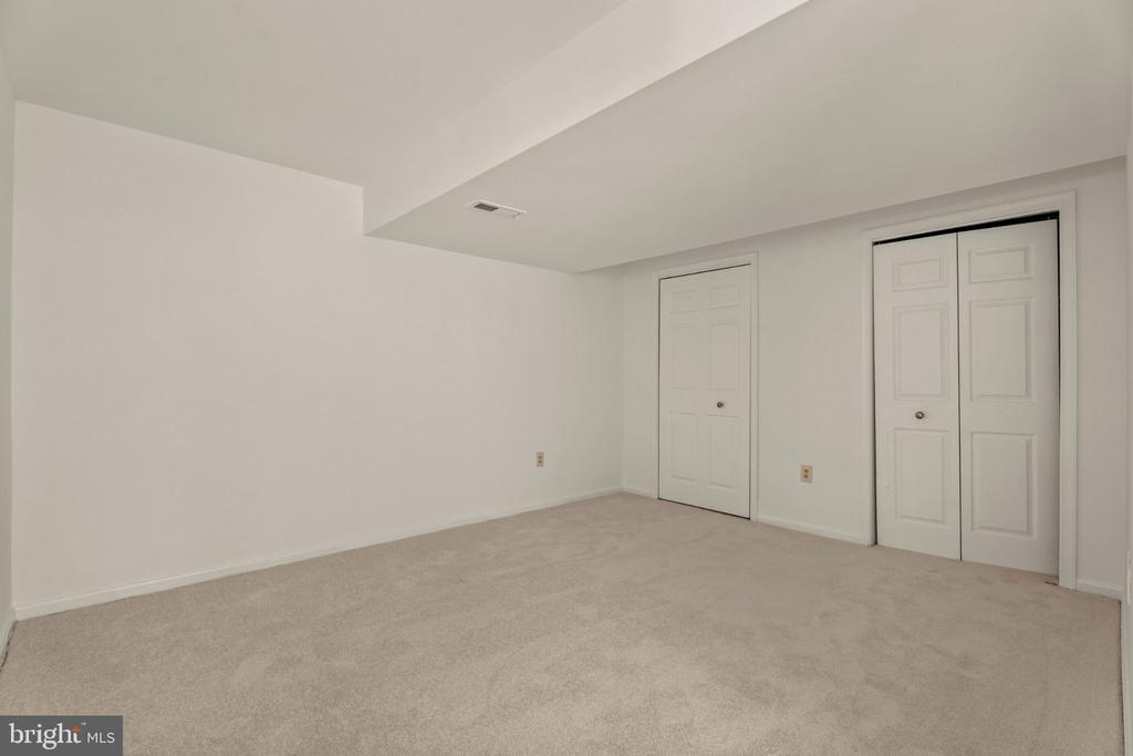 Empty carpeted room with a single door and double-door closet.