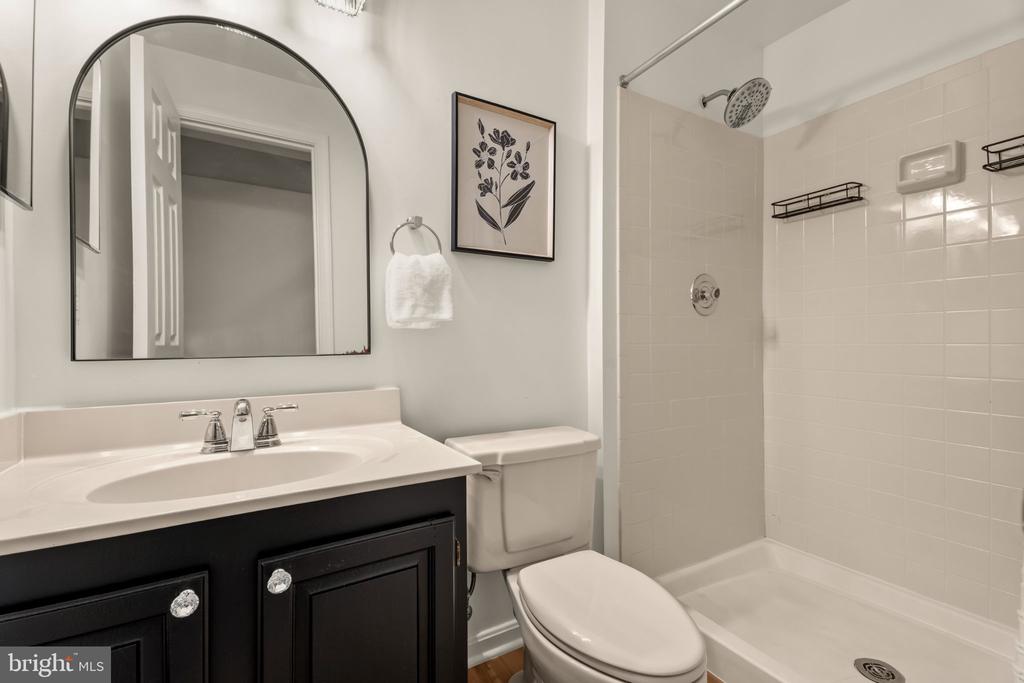 Bathroom with black vanity, arched mirror, and tiled tub-shower.