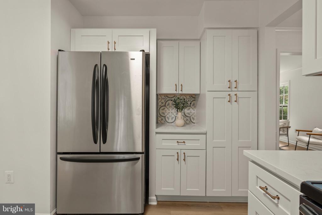 Kitchen with a stainless steel refrigerator, white cabinetry, and patterned tile backsplash.