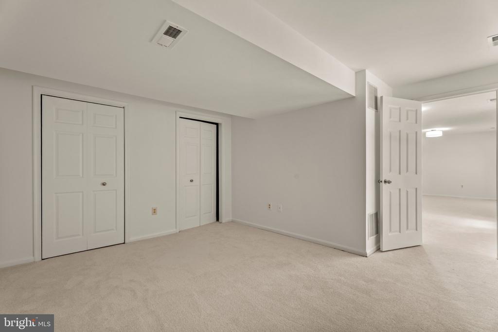 Vacant carpeted room with two closets and an open doorway to an adjoining room.