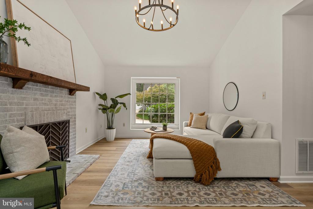 Living room with a white sectional, brick fireplace, green accent chair, and large daylight window.